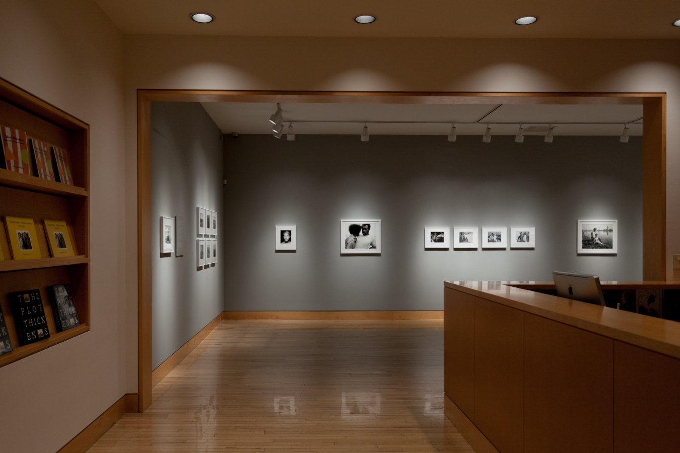 Color image of gallery entryway exhibiting black and white photographs on grey gallery walls