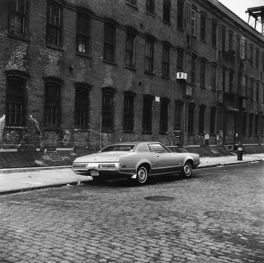Black and white photograph of a car on an empty street
