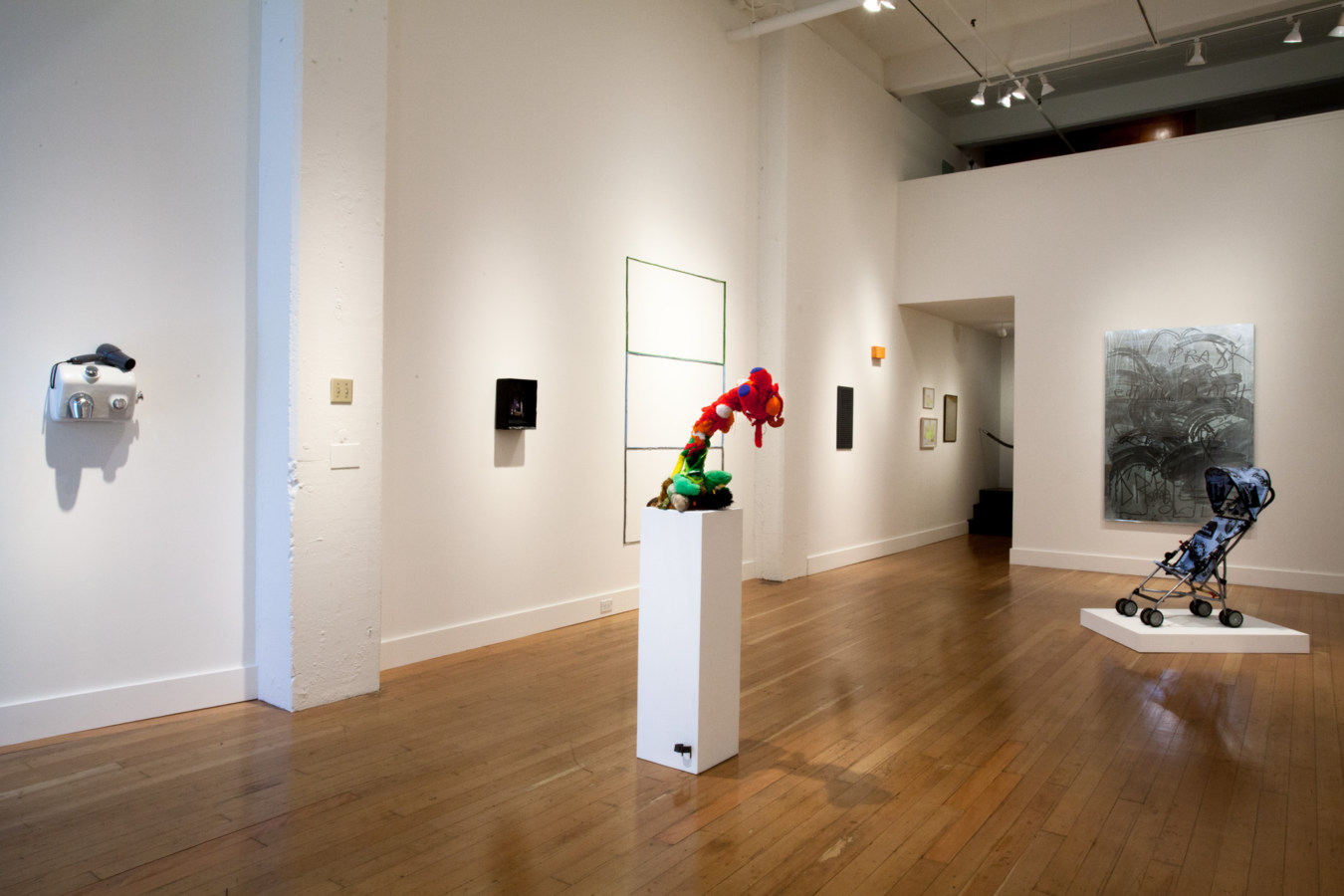 Color image of mixed media and sculptural works in white walled gallery