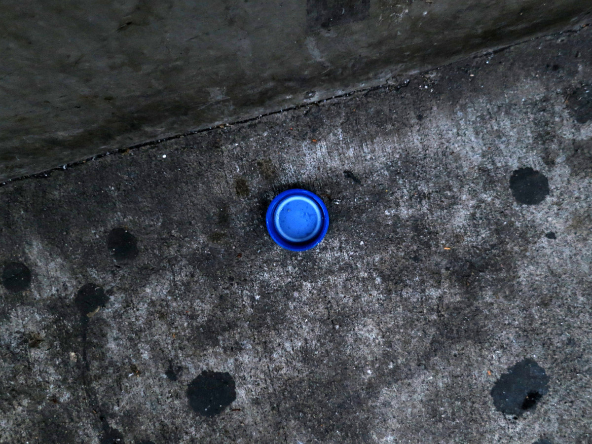 A photograph of a blue plastic bottle cap on the street.