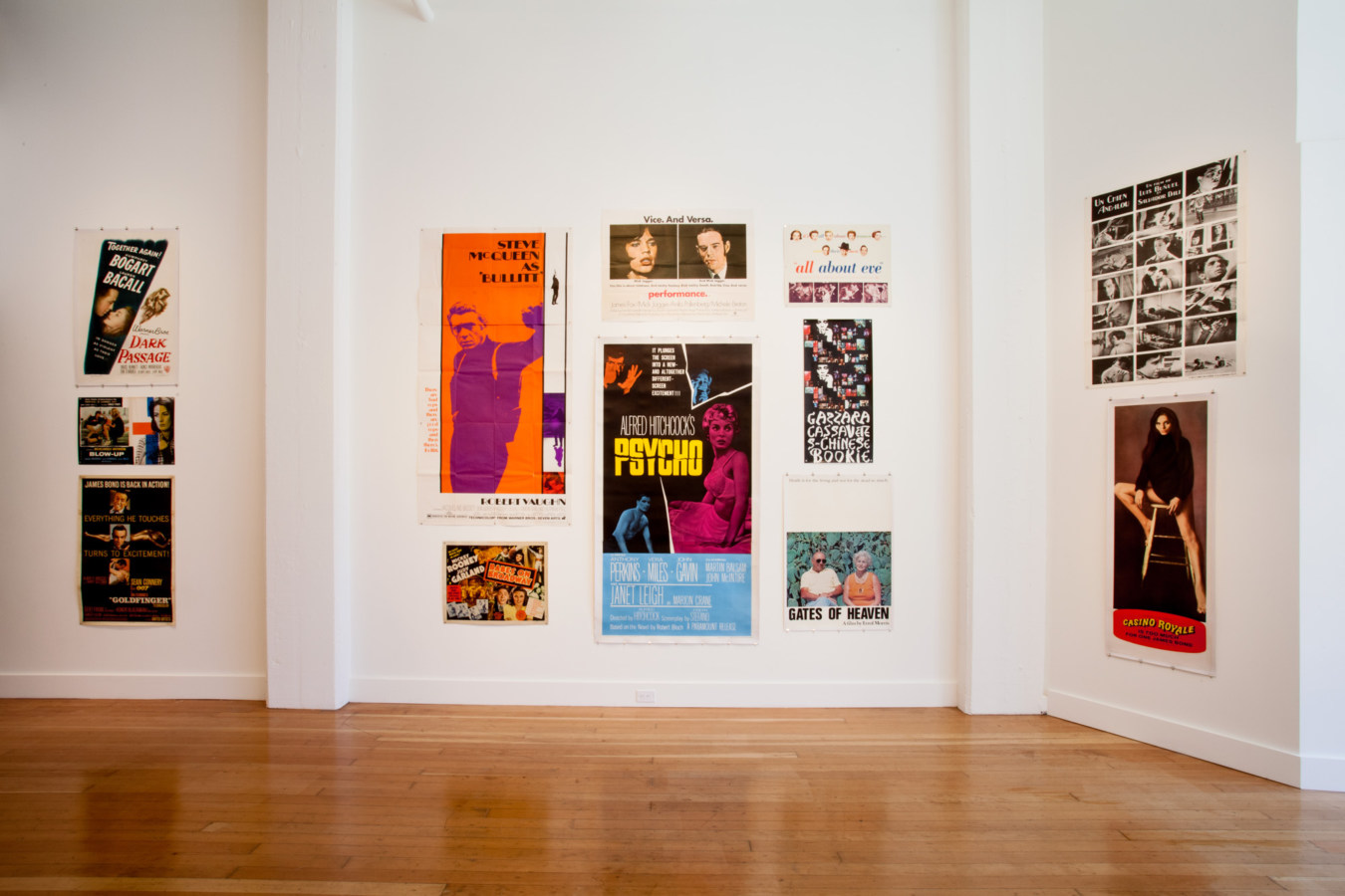 Color image of white walled gallery exhibiting various sized movie posters