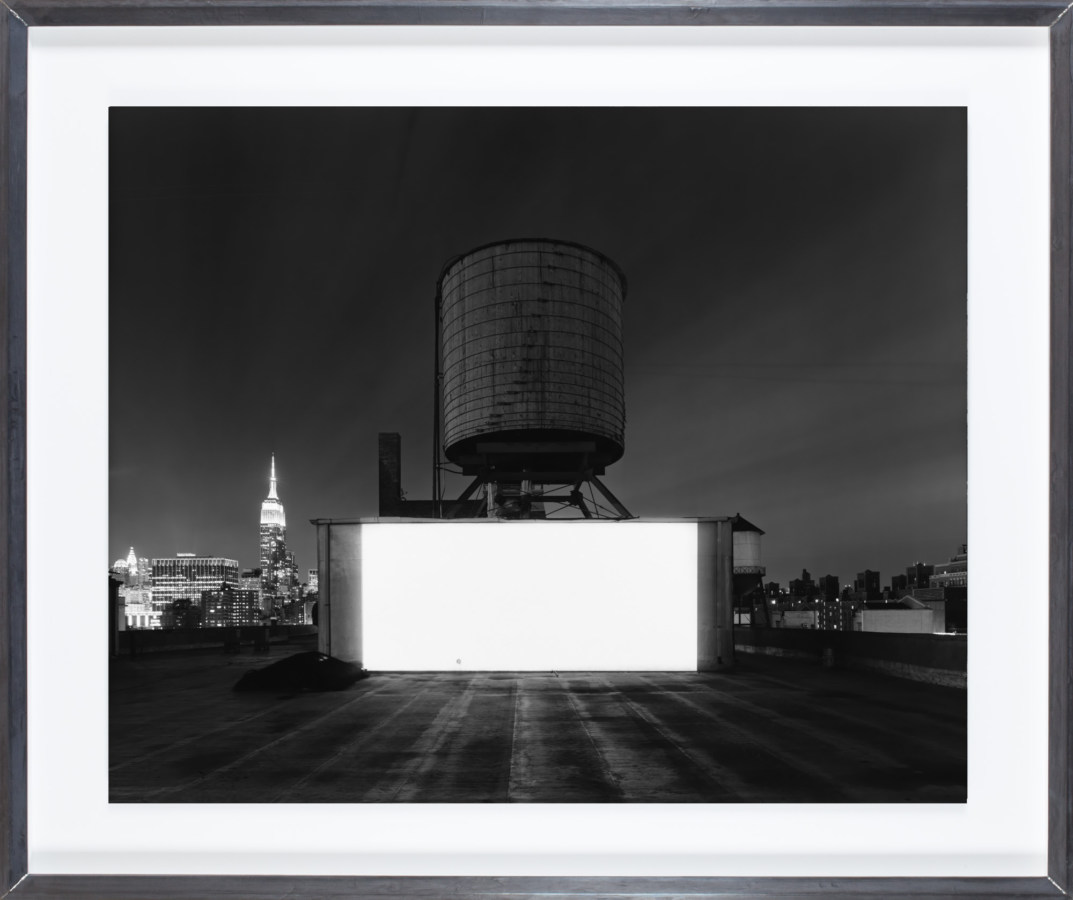 Black and white photograph of a large white theater screen on a rooftop