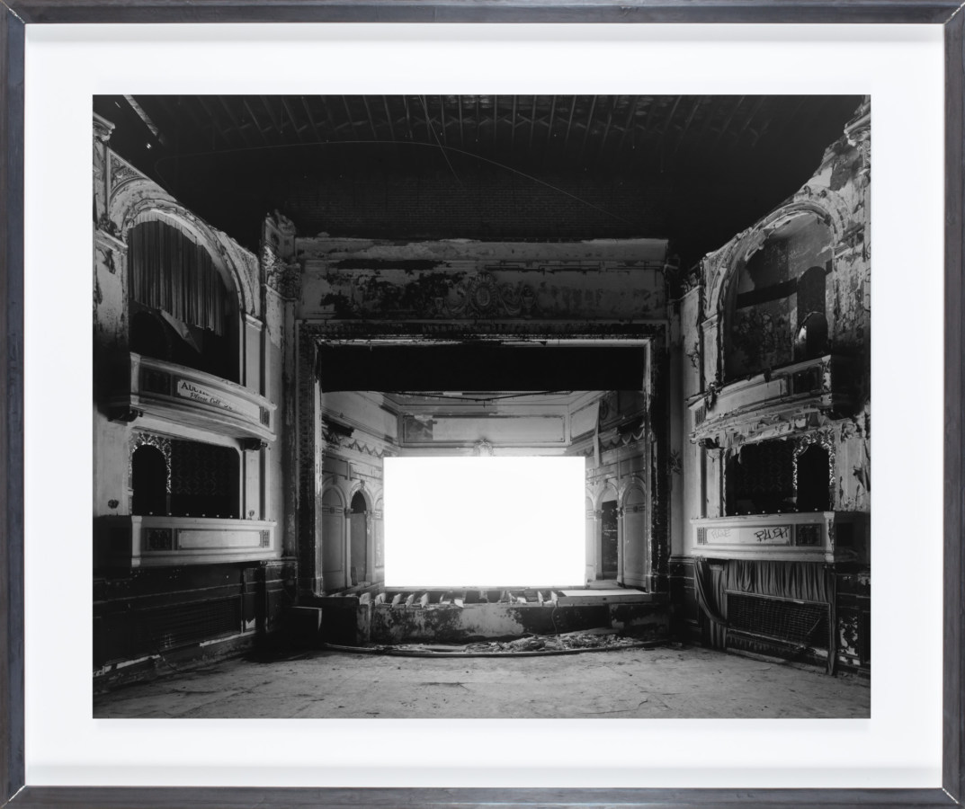 Framed black and white photograph of an empty theater with large white screen