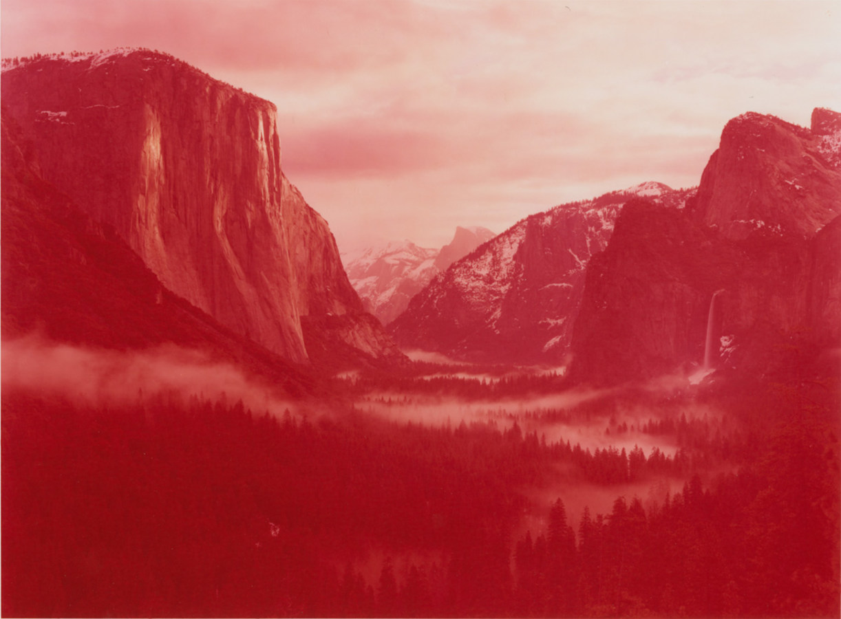 Color photograph of mountainous valley during sunrise hued in red