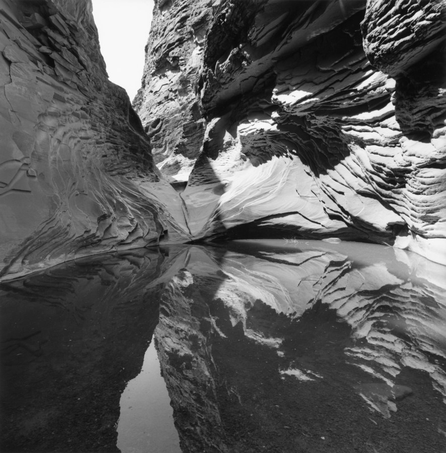 Black-and-white photograph of rock formations and their reflection in a body of water