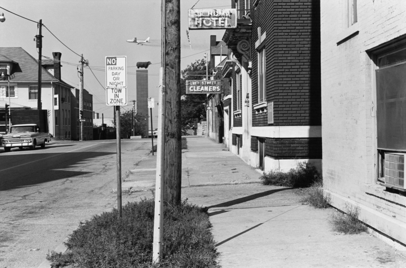 Black-and-white photograph of a city street with a telephone pole in the center