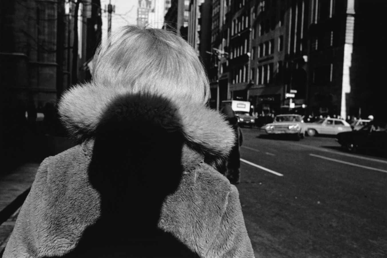 Black-and-white photograph of the shadow of a persons head on the back of a woman