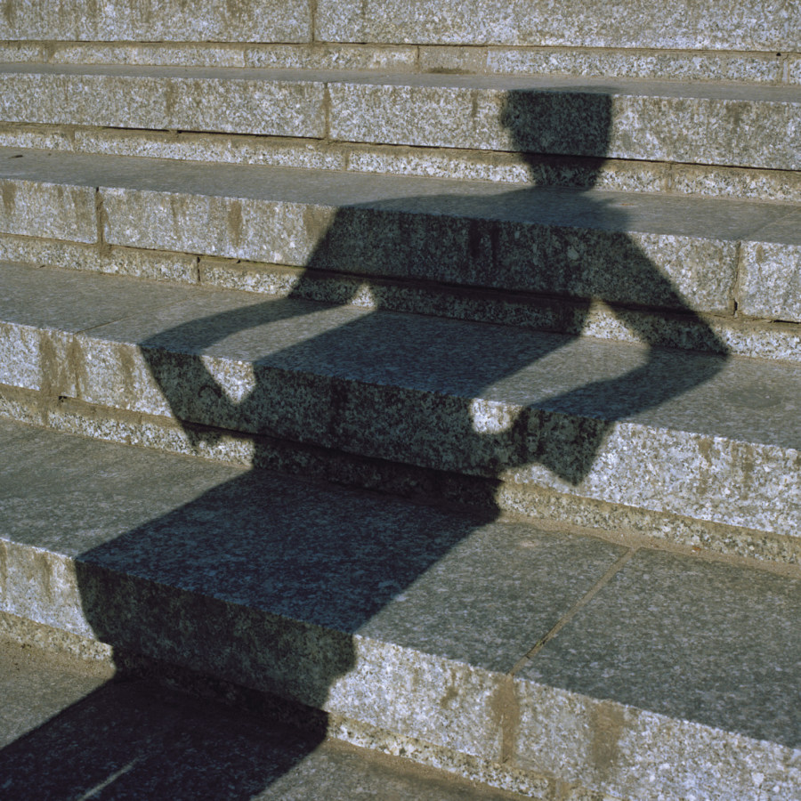 Color photograph of concrete steps and shadowy figure with arms at side