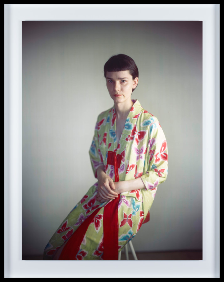 Color photographic portrait of a young woman with short hair and bangs dressed in a flower-patterned robe