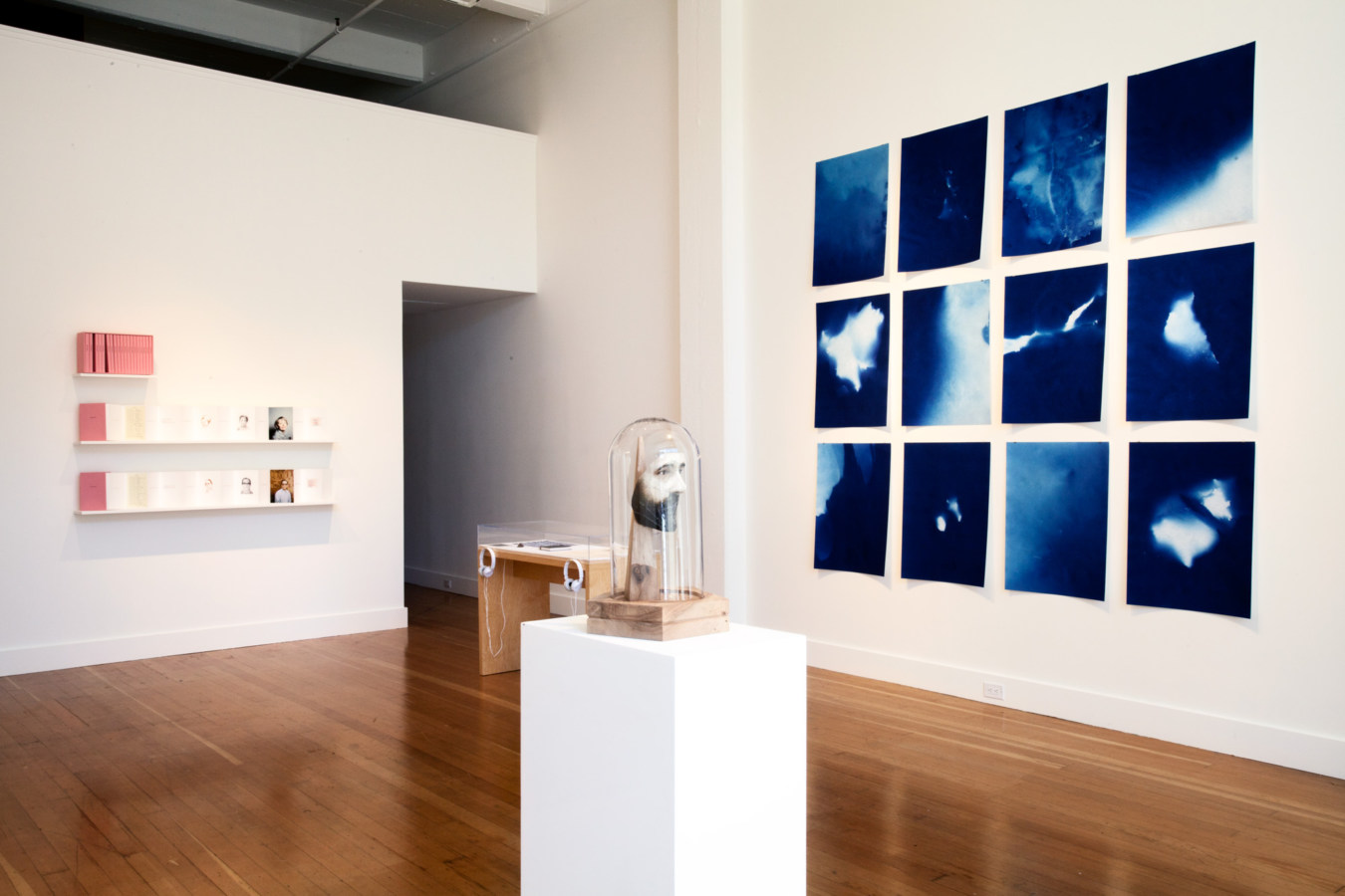 Color image of white walled gallery exhibiting sculptural and framed artworks