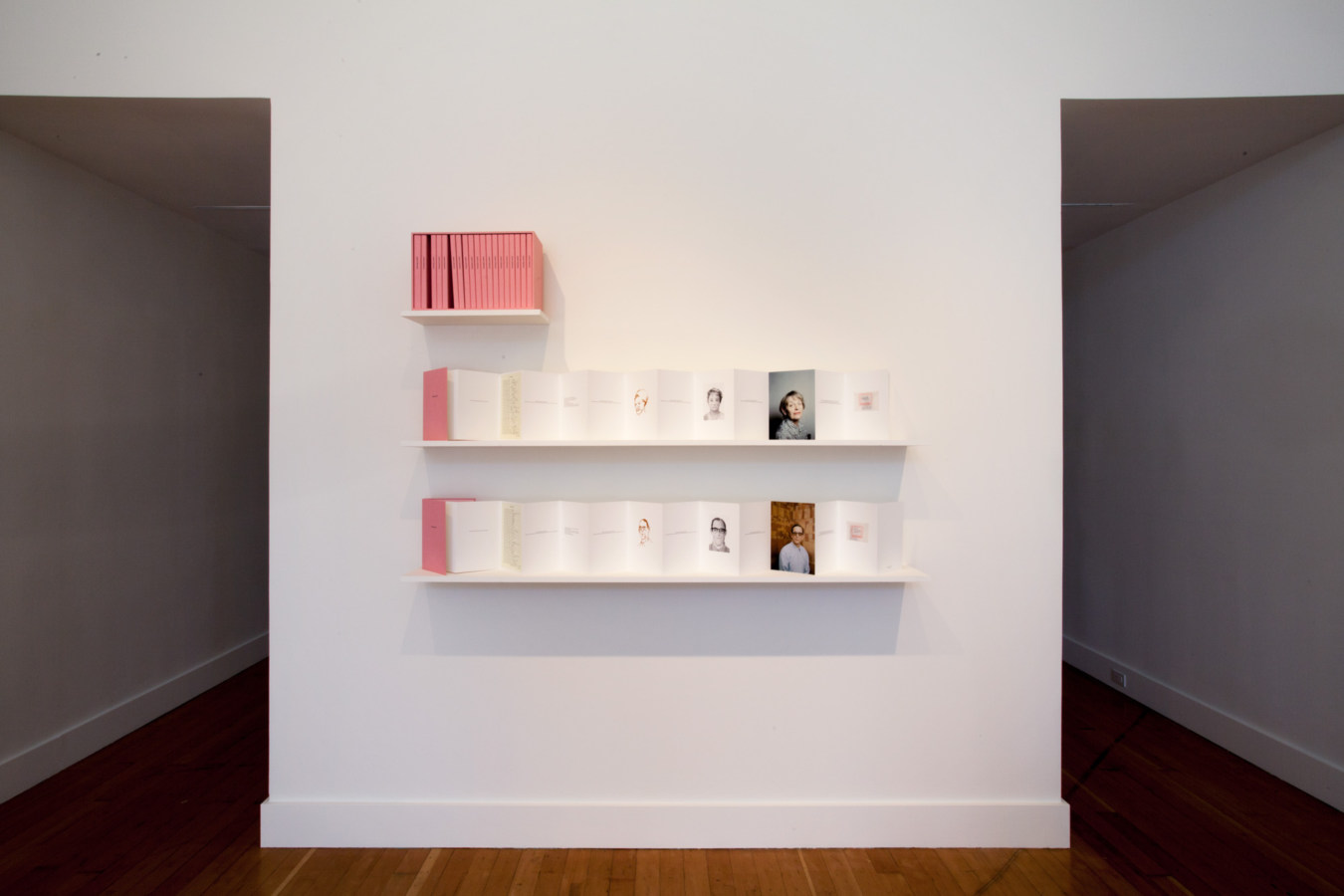 Color image of white gallery wall exhibiting publication box set