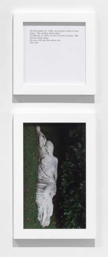 A square framed text panel hanging over a framed photograph of a sculpture of a woman lying on the ground