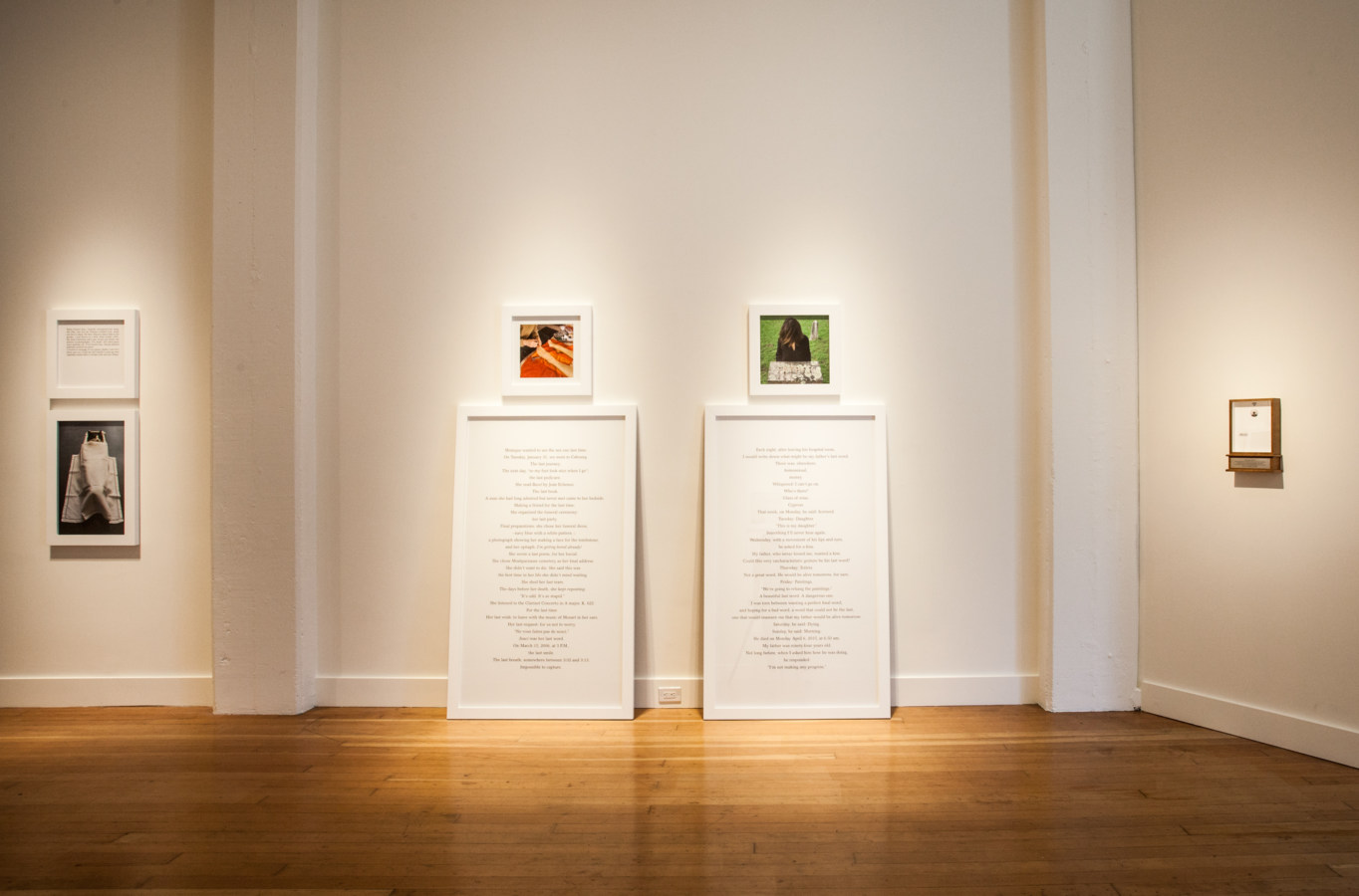 Color image of white walled gallery exhibiting framed photographs and text