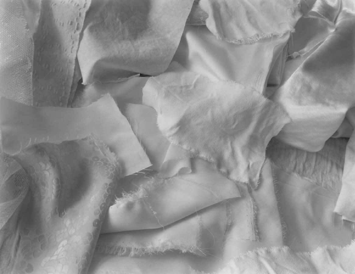 Black-and-white photograph of cut and torn scraps of white fabric