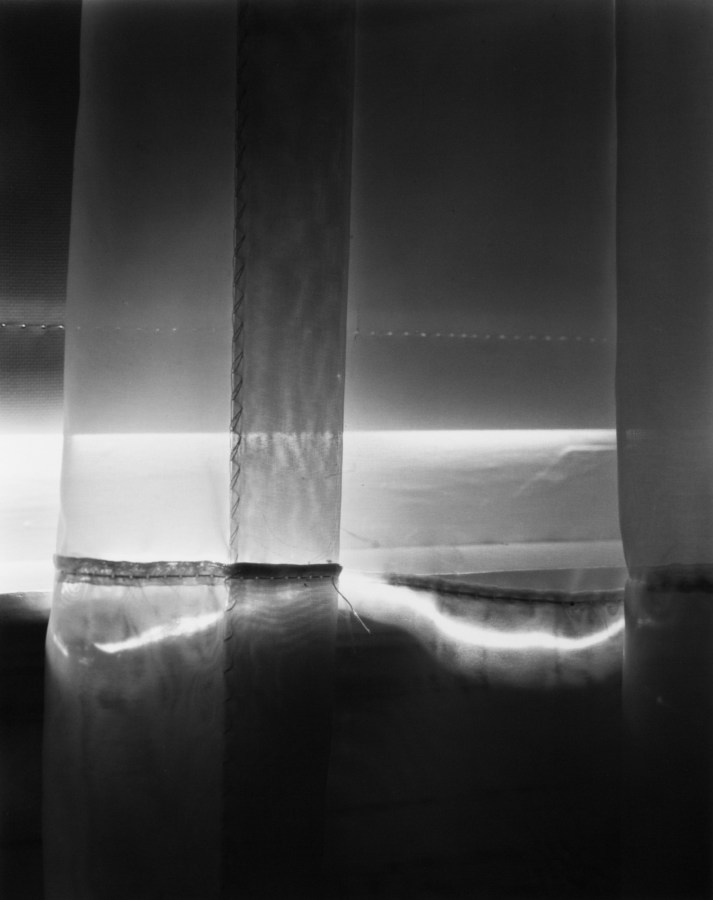 Black-and-white photograph of light and shadow through a curtain