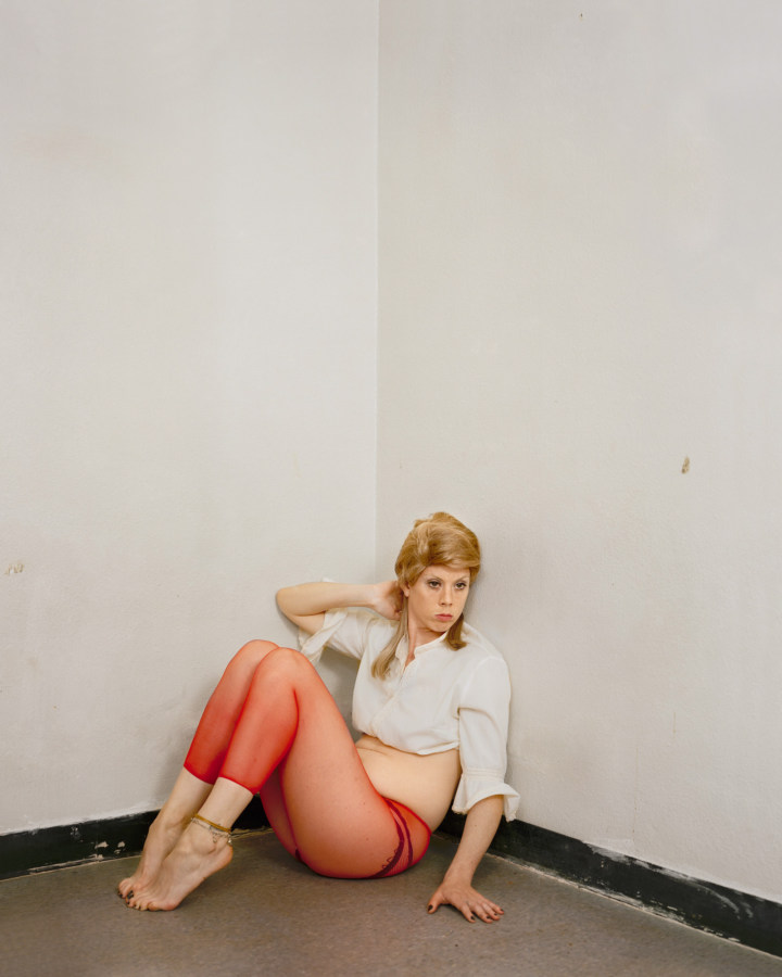 Color photograph of a woman posing in the corner of a room