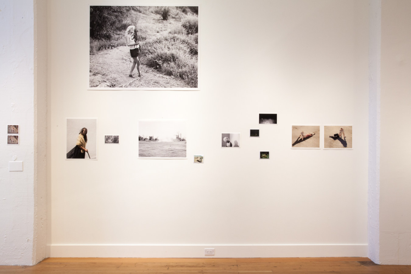 Installation photograph of a gallery space with small and large unframed prints on white wall