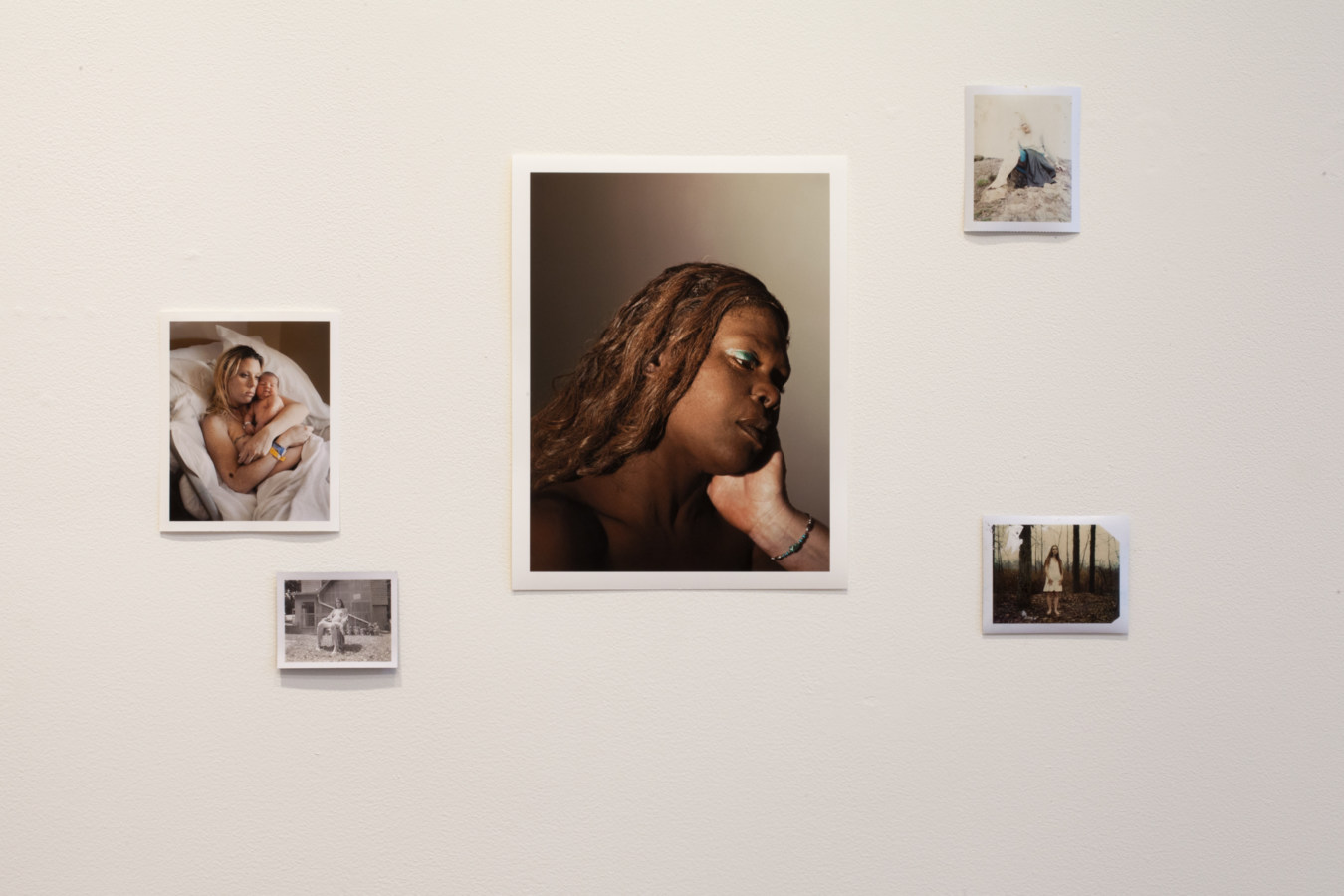 Installation photograph of a gallery space with small unframed prints on white wall