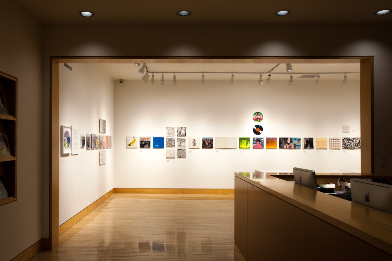 Color image of gallery entryway exhibiting vinyl records and record sleeves on white gallery walls