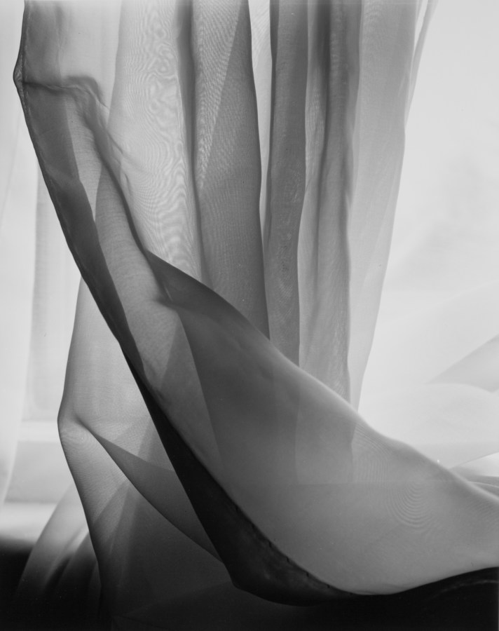 Black-and-white photograph of light through a crumpled sheer curtain