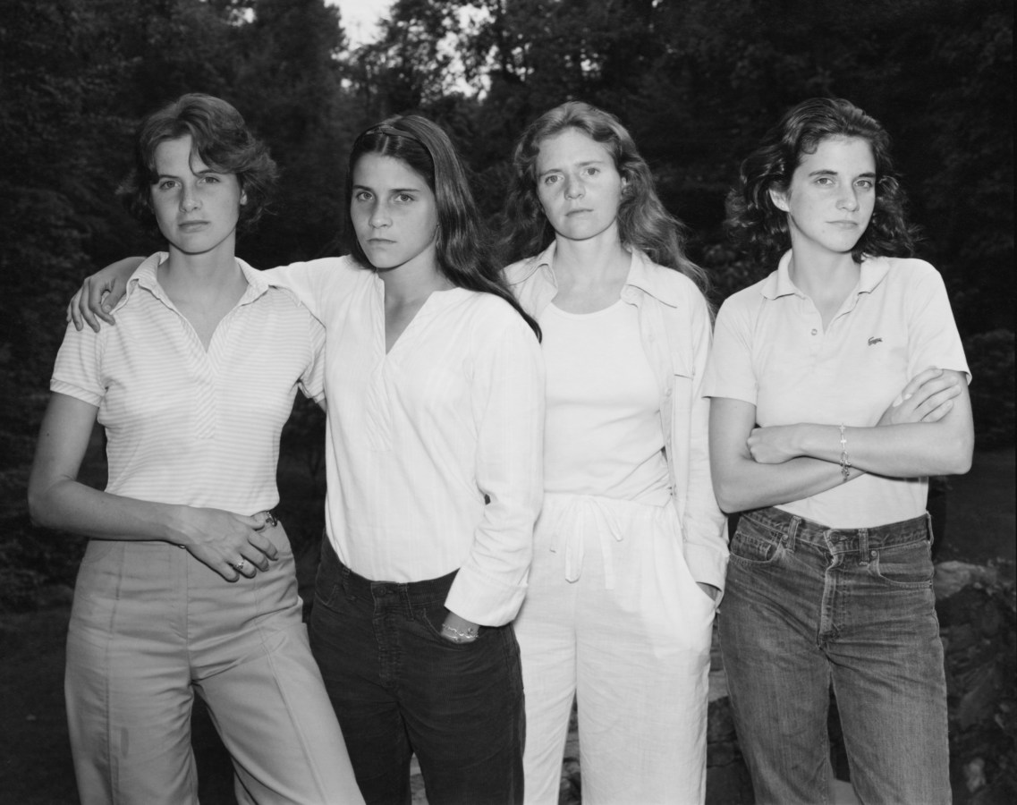 Black and white photograph of four women standing shoulder to shoulder in a garden