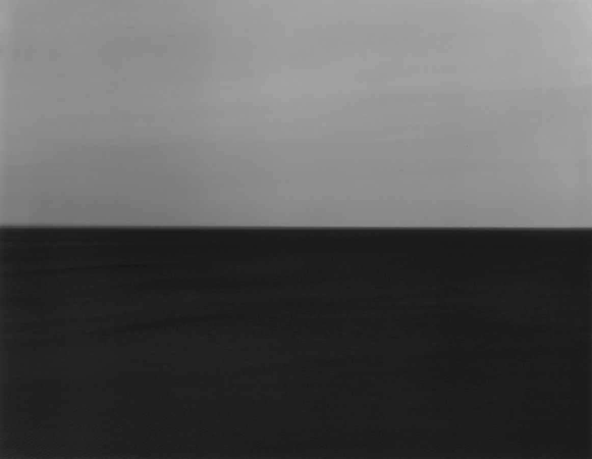Black-and-white photograph of a seascape with a dark gray sky and very dark water