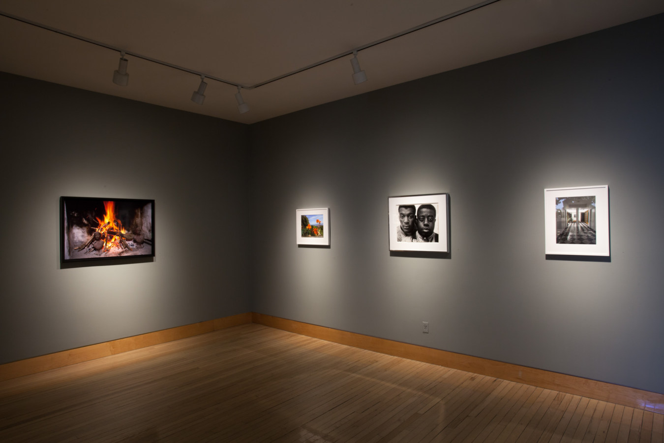 Color image of color and black and white photographs on grey gallery walls