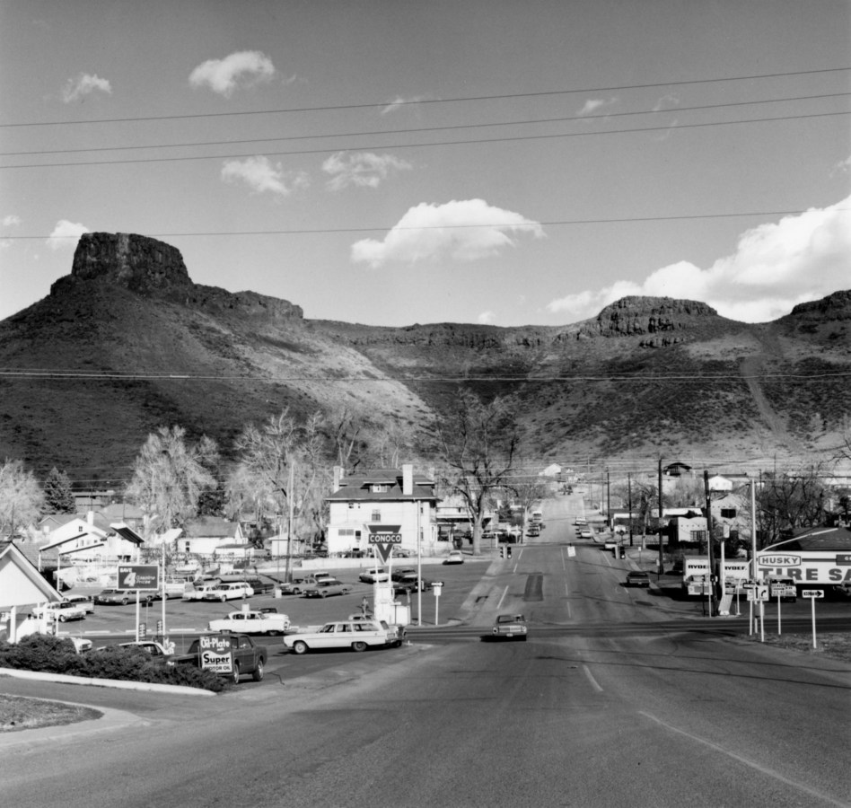 Black and white photograph of small town situated against a mountainous background