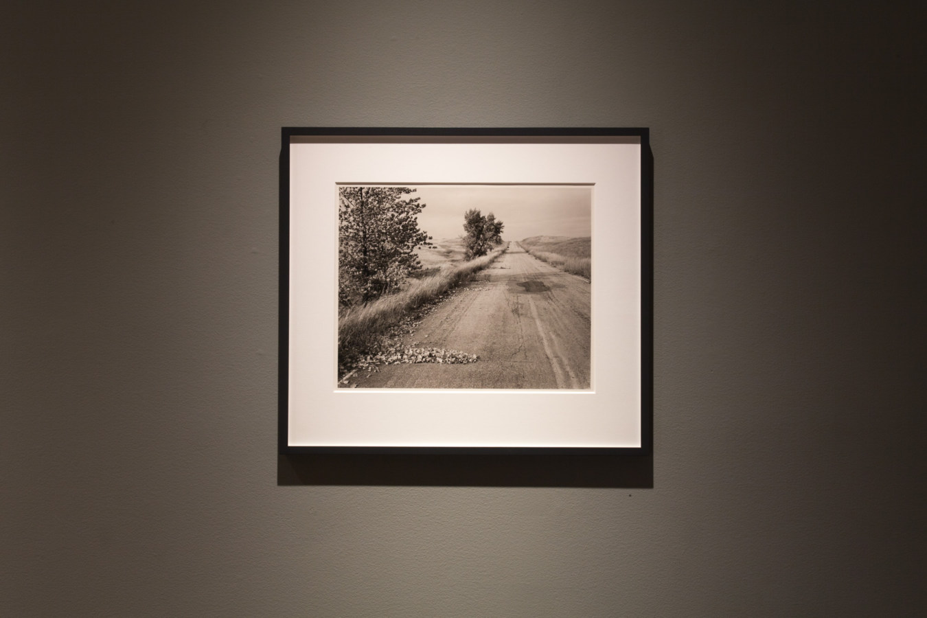 Color image of framed black and white photograph on grey gallery wall