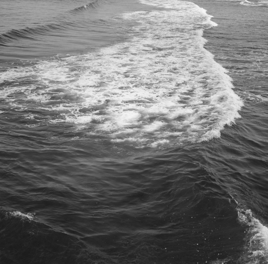 Black-and-white photograph of a wave moving from left to right and the trail of white water following it