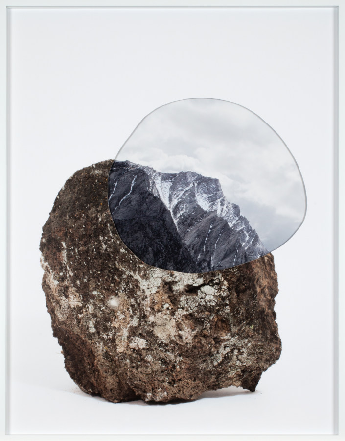 A framed photograph of a rock with a cutout of a photograph of a mountain ridge
