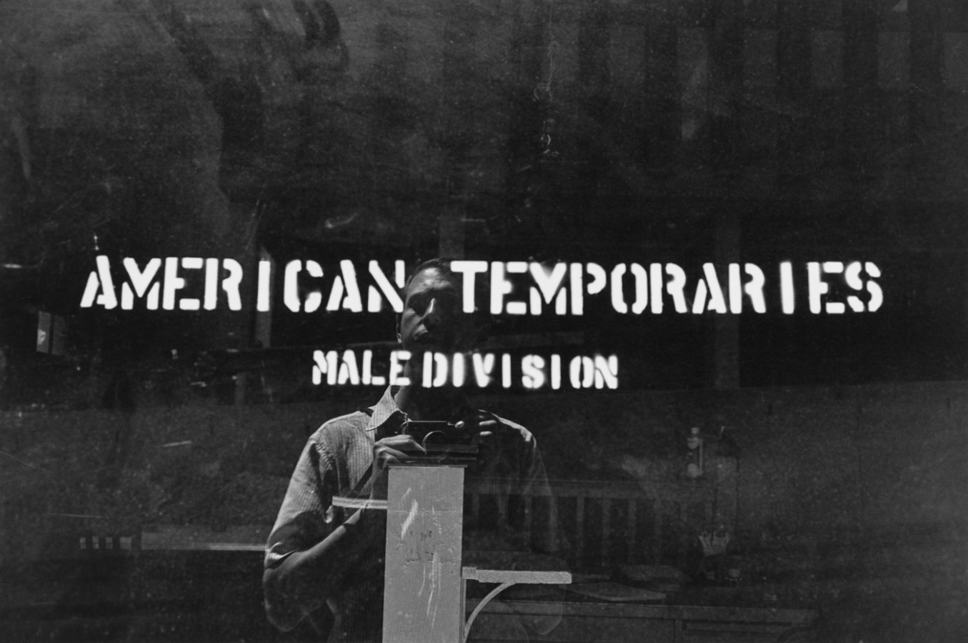 Black and white photograph of signage taken from the exterior with reflection