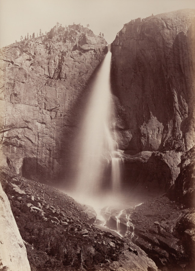 Black and white photograph of waterfall within rocky valley
