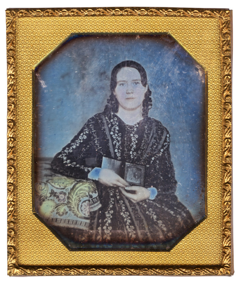 Cased daguerreotype portrait of a white woman holding a daguerreotype.