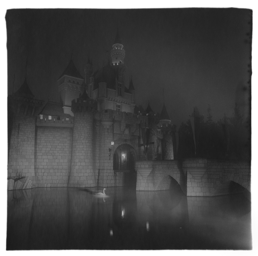 Black-and-white photograph of a dramatically lit castle at night with fog