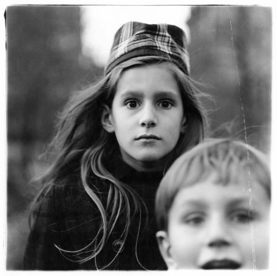 Black-and-white photograph of a girl wearing a hat and a young boy in the bottom right corner of the frame