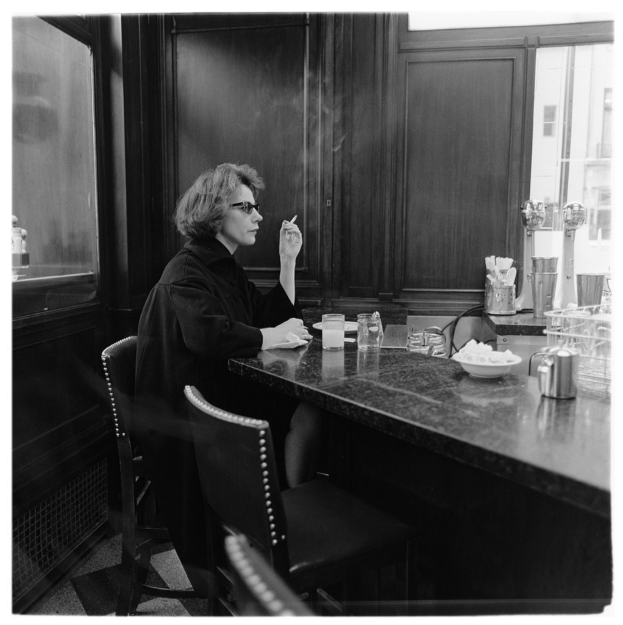 Black-and-white photograph of a woman sitting alone at a counter