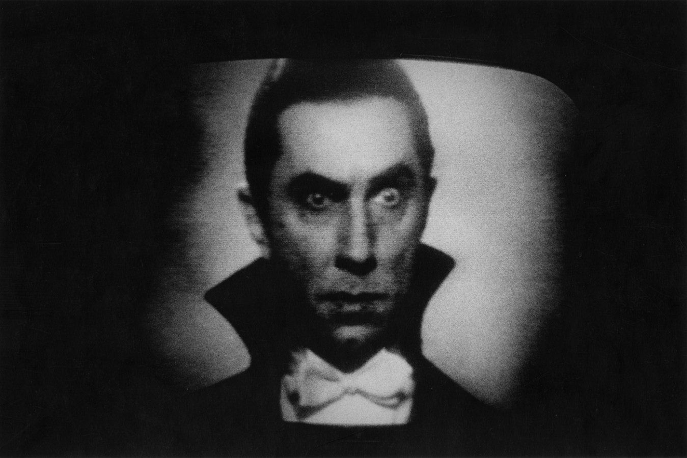 Black-and-white photograph of Dracula with one eyebrow raised on a movie screen