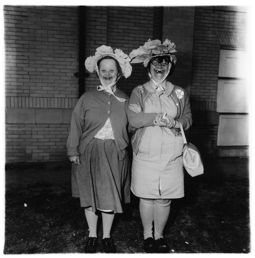 Black-and-white photograph of two women wearing hats with a building in the background