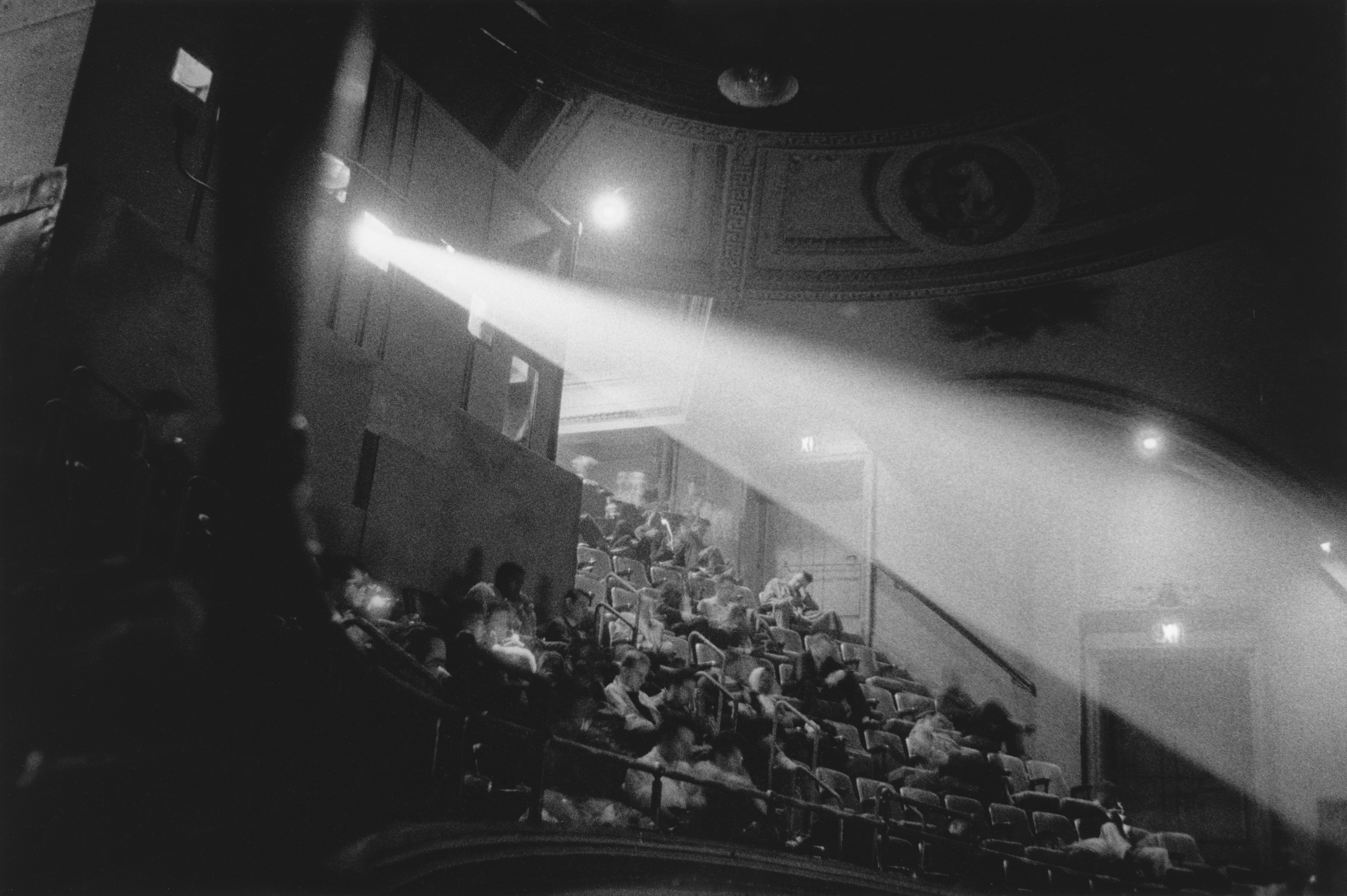 Black-and-white photograph of light from a movie projector streaming across a balcony