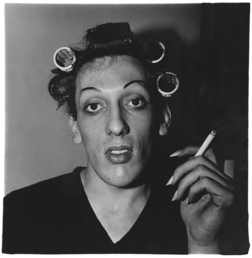 Black-and-white photograph a man with curlers in his hair holding a cigarette