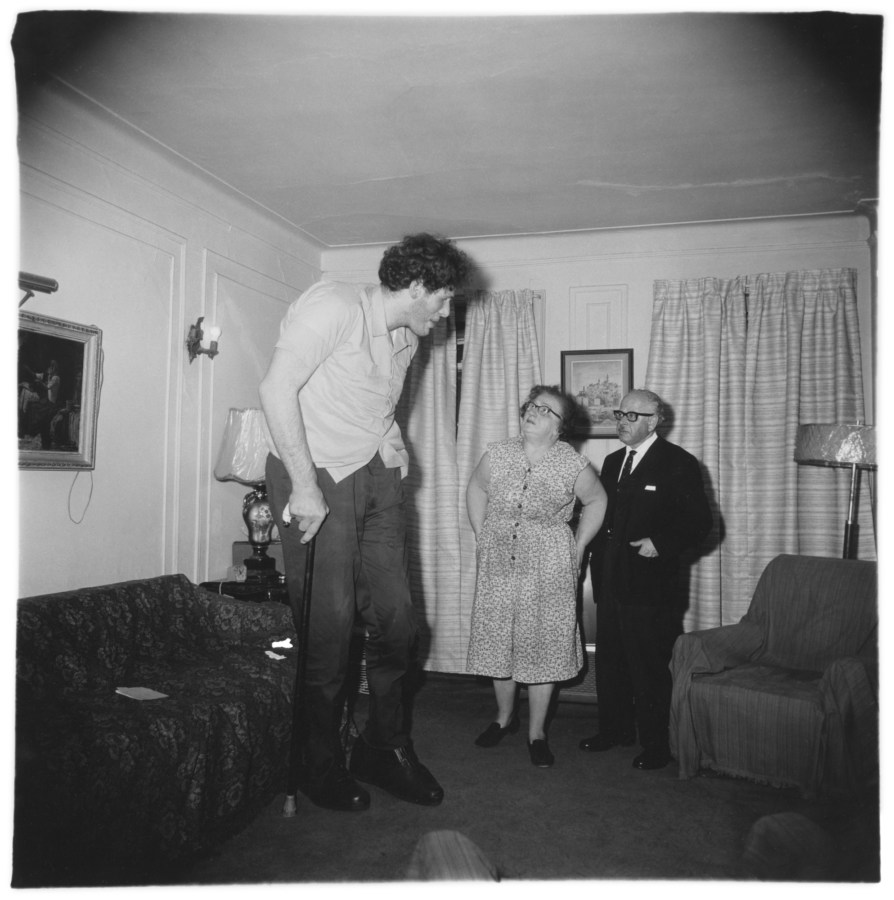 Black-and-white photograph of three figures standing in the center of a living room