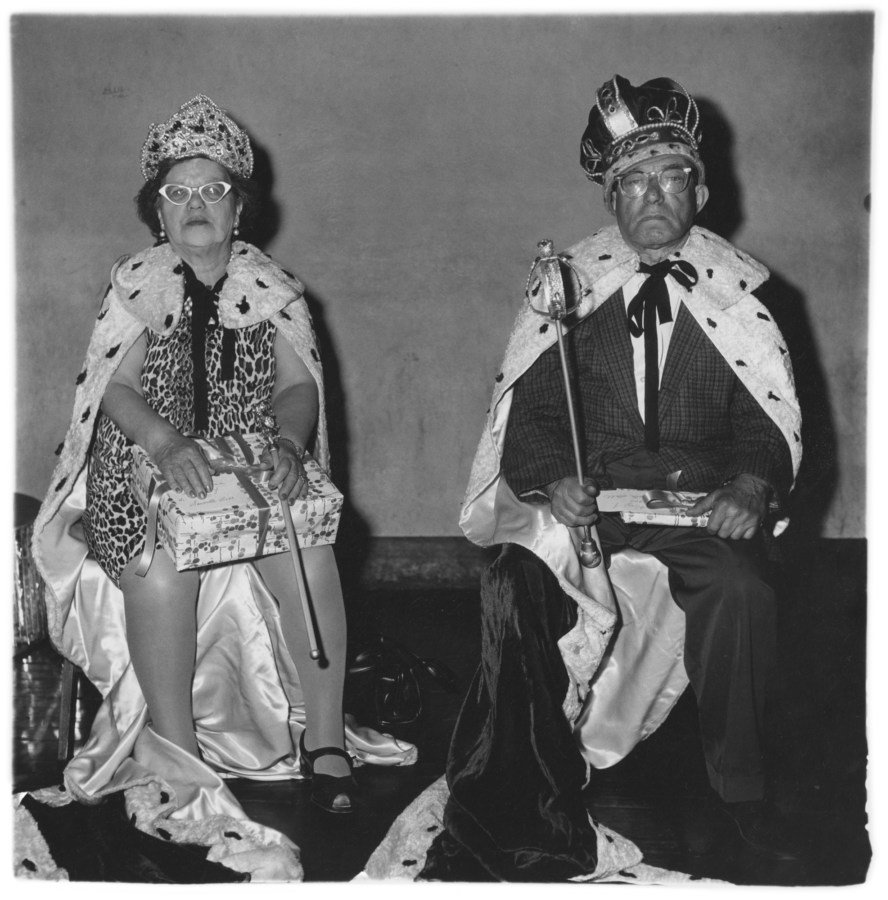 Black-and-white photograph of an elderly couple wearing king and queen costumes