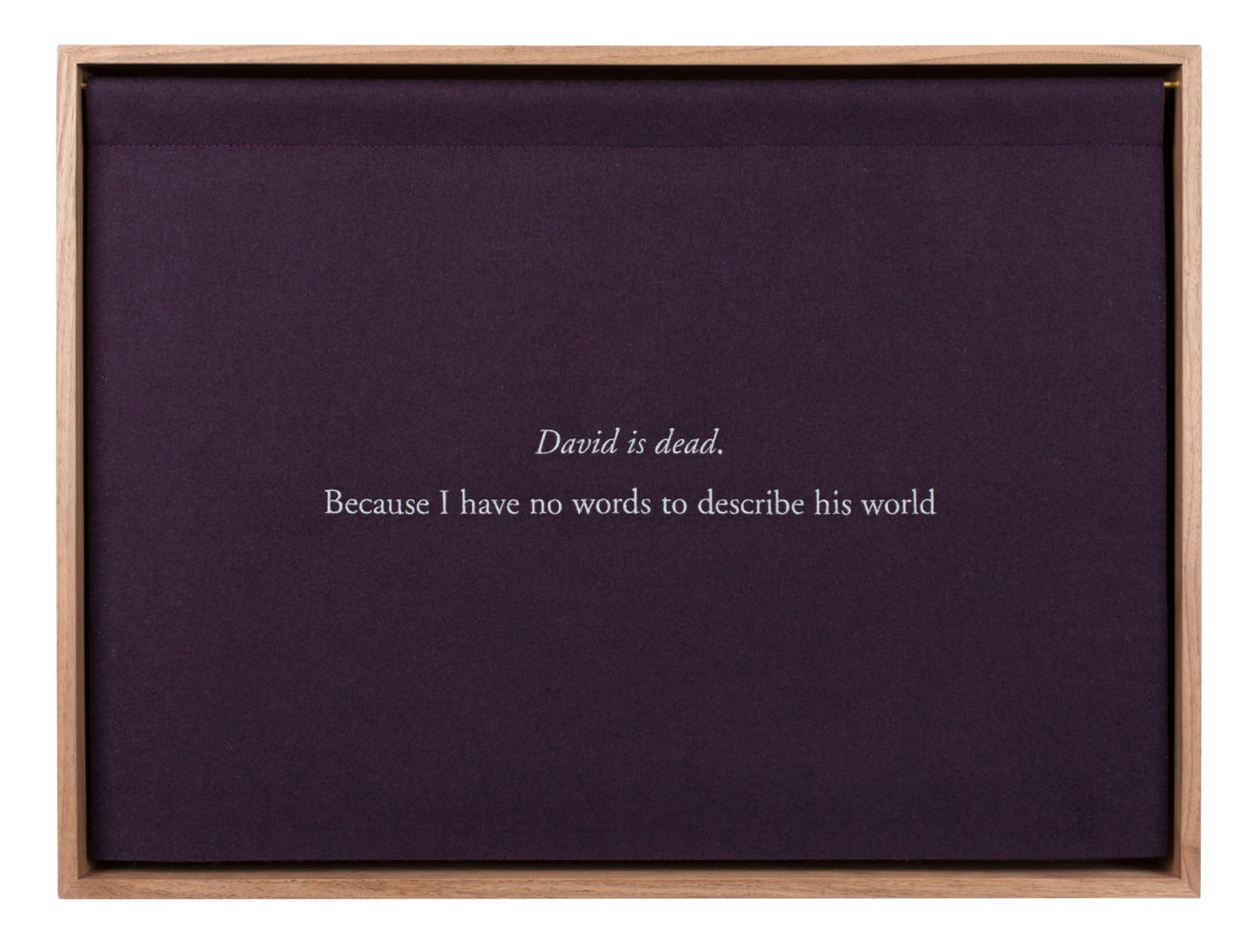 A wooden box with a purple curtain, embroidered with white text "David is dead. Because I have no words to describe his world."