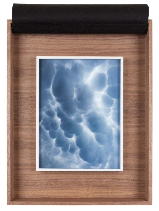 A framed photograph of clouds in the sky, inside a wooden box