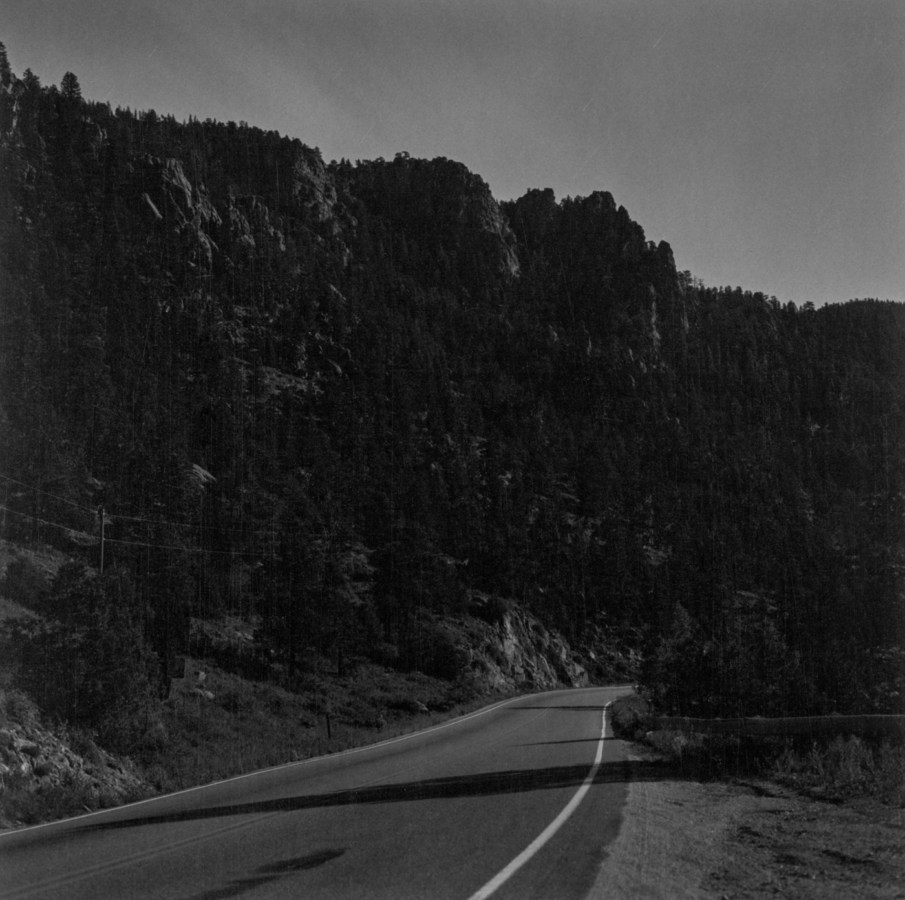A black and white photograph of a road through a canyon at night