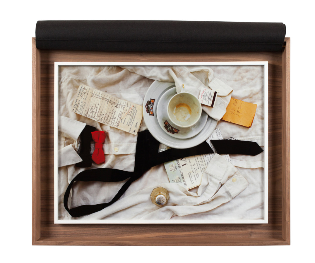 A box with a photograph of a waiter's uniform, with a cup and saucer, a pepper shaker, and checks on top