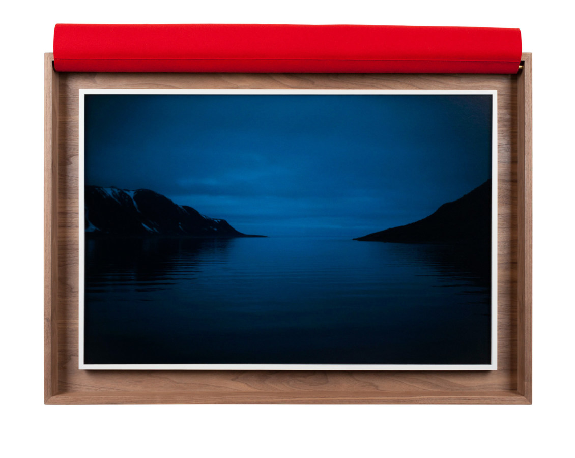A framed photograph of a body of water, reflecting a dark blue sky, with small land masses on either side.
