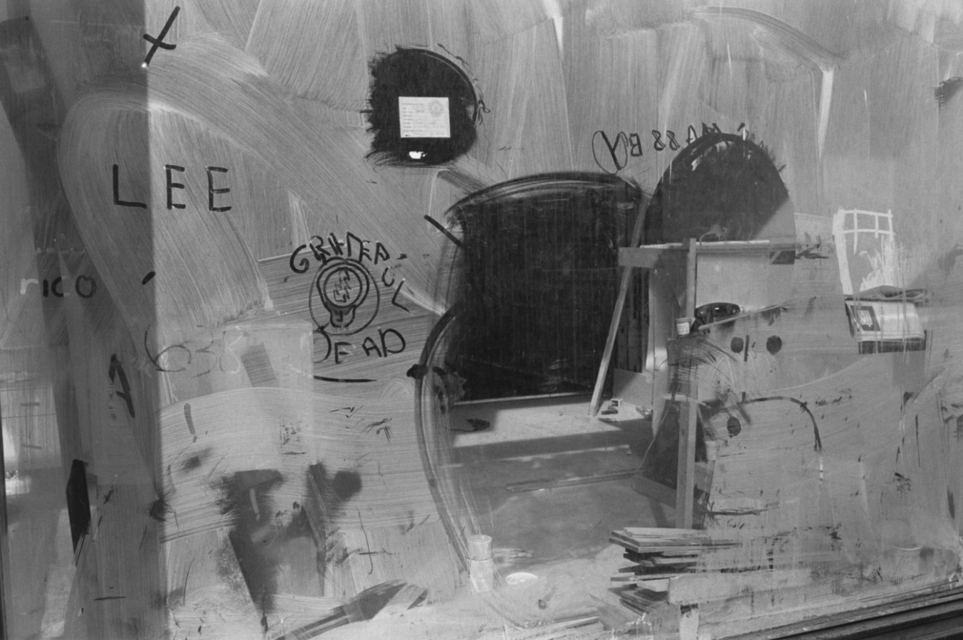 Black and white photograph of a storefront window with graffiti