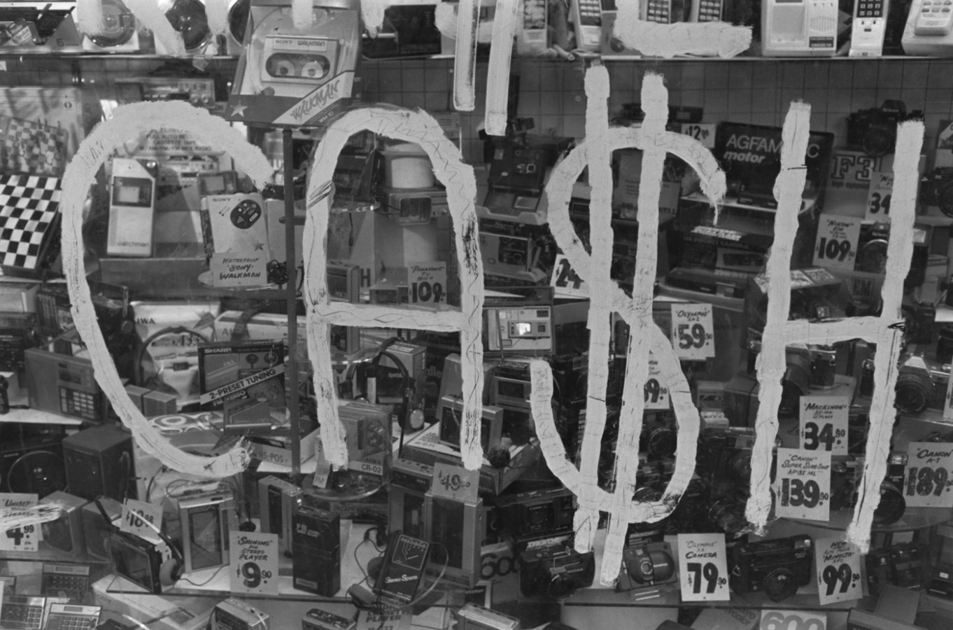Black and white photograph of a sign that says cash with products in the background
